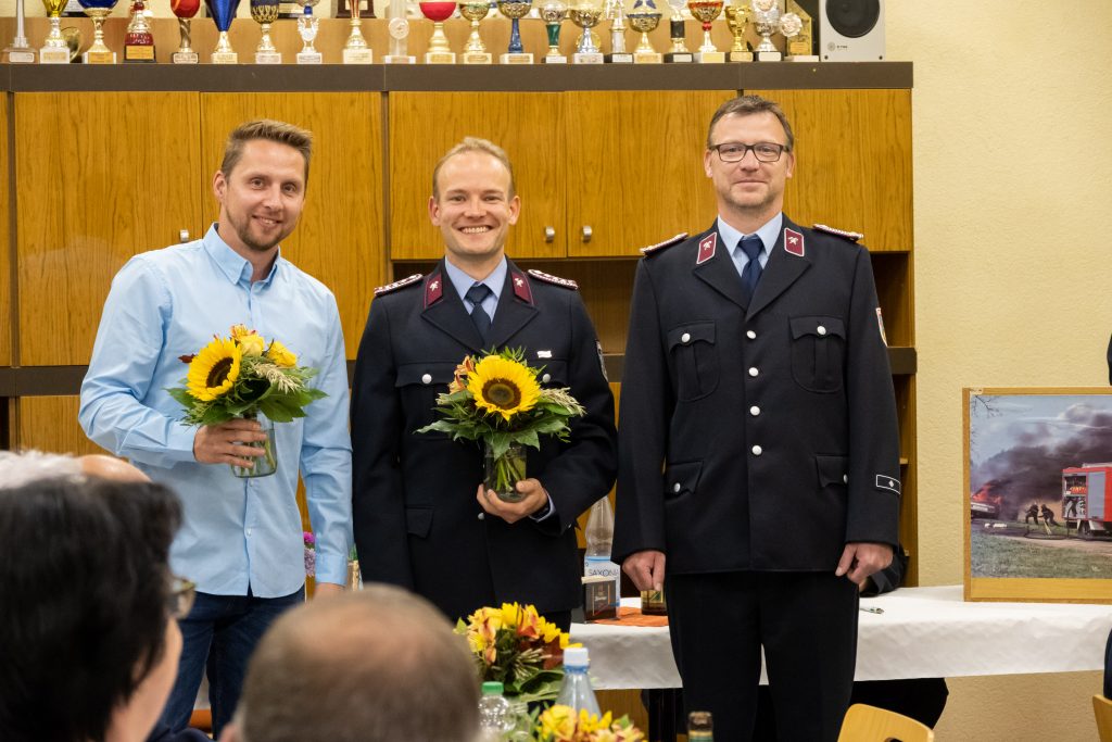Drei Männer halten Blumensträuße - neue Wehrführung bei der Feuerwehr Untschen